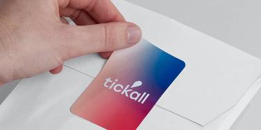 Hand putting a rectangle label with Tickall logo on gradient background on a white envelope